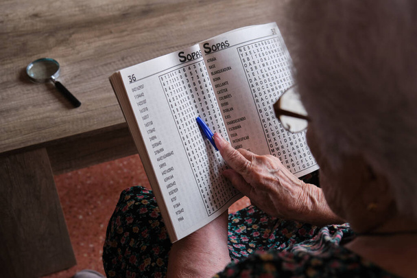 senior woman spending retirement time playing word search at home - Foto, imagen