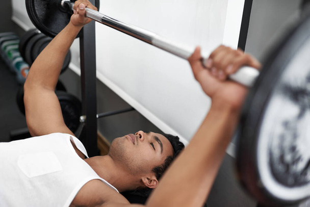 Working on his upper body. A young ethnic man exercising in the gym - Photo, Image