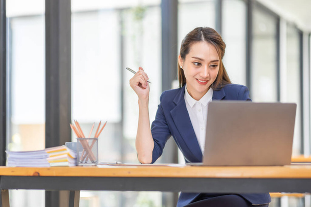 Brown haired wearing light blue jacket smiling Asian woman work with document laptop in office, doing planning analyzing the financial report, business plan investment, finance analysis concept. - Фото, зображення
