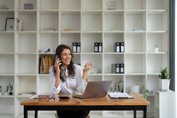 Bizneswoman korzystająca z laptopa i rozmawiająca przez telefon. - Zdjęcie, obraz