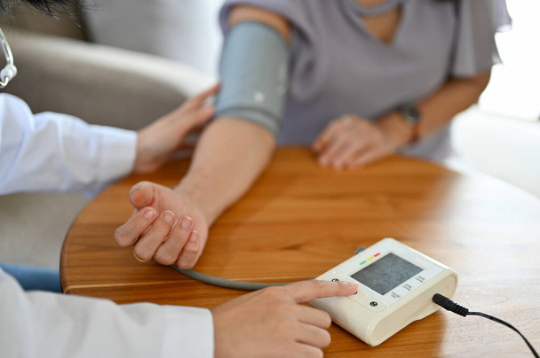 Жінка-лікар або медсестра перевіряє кров'яний тиск та частоту серцевих скорочень пацієнта з монітором кров'яного тиску. крупним планом зображення рук
 - Фото, зображення