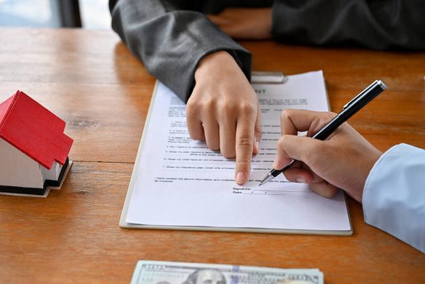 Una cliente donna firma la sua firma su un contratto di noleggio durante l'incontro con un broker immobiliare femminile. colpo ritagliato - Foto, immagini