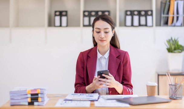 Boldog izgatott ázsiai fiatal vállalkozó üzletasszony telefonhívás és laptop ül egy íróasztal tiszt a nap az irodában - Fotó, kép
