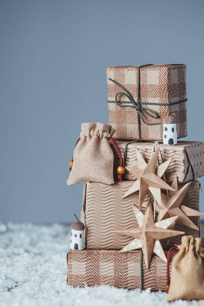 Árbol de Navidad con regalos en la nieve sobre fondo gris. Decoración de Navidad sostenible orgánica DIY. Consumo ético y concepto ecológico. espacio para el texto. Foto de alta calidad - Foto, imagen