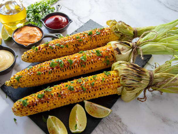 three heads of yellow corn grilled lemon lime spicy, white orange red sauce - Photo, image