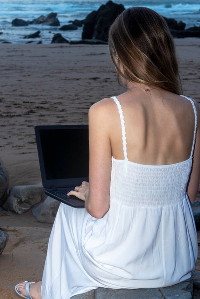 Donna che lavora a distanza sulla spiaggia ai tropici. Lavorare in remoto sul computer portatile tramite Internet. Lavorare durante il viaggio. - Foto, immagini