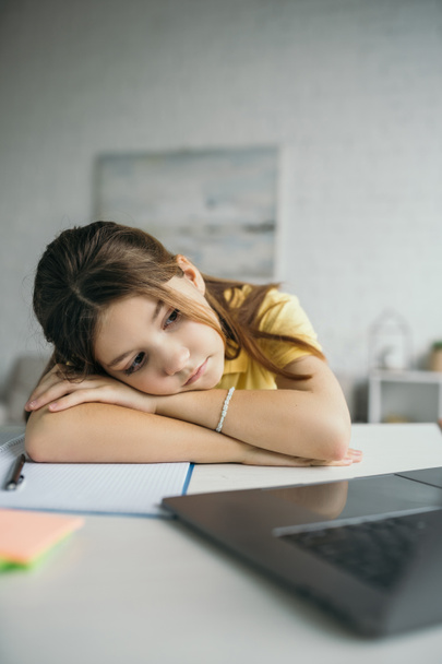tired girl lying on table near notebook and laptop with blank screen at home - Photo, Image