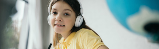 smiling girl looking at camera while listening music in headphones, banner - Photo, image
