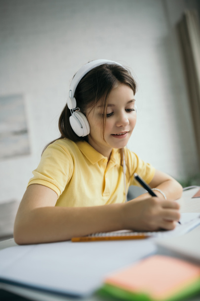 θετική κοπέλα στα ακουστικά γραπτώς, ενώ η μάθηση στο σπίτι - Φωτογραφία, εικόνα