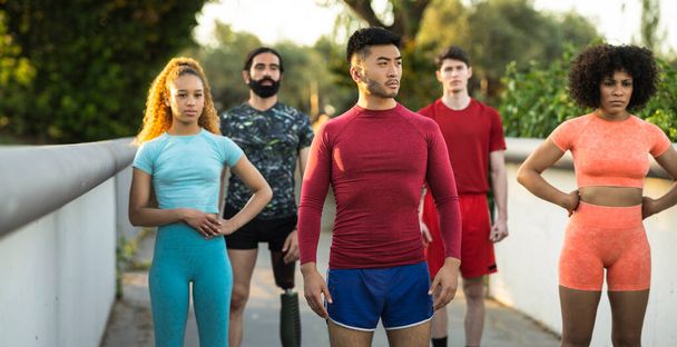 Çok ırklı bir grup koşucu ciddi bir ifadeyle ayakta duruyor. Asyalı adama odaklan. - Fotoğraf, Görsel