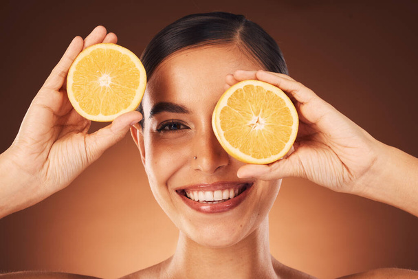Кожа, женщина и портрет с оранжевым лицом для витамина С, эстетического и косметического увеличения. Модель здоровья, хорошего самочувствия и самочувствия с улыбкой для кампании по дерматологии цитрусовых в коричневой студии - Фото, изображение