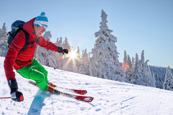 Skifahrer fährt im Hochgebirge vor blauem Himmel abwärts. - Foto, Bild