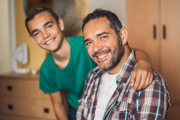 Portrait of happy father and son at home. They are embracing. - Foto, Imagem
