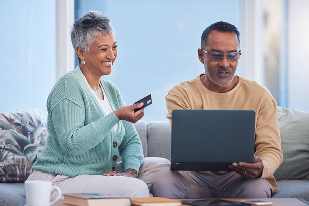Couple, laptop and credit card for ecommerce, online shopping or transaction together at home. Elderly man and woman with smile for easy internet banking on computer relaxing on living room sofa. - Фото, изображение