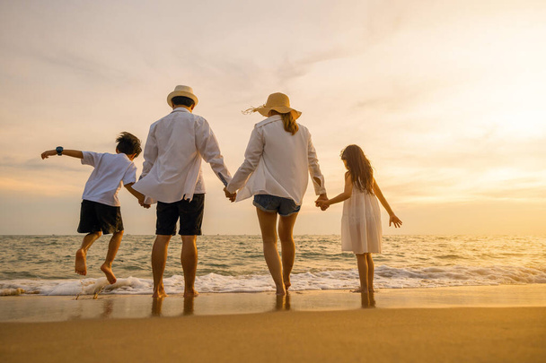 Silhouette of family holding hands live healthy lifestyle on beach, Happy Asian family have fun jumping together on beach in holiday sunset time, Back people enjoying travel trip and summer vacations - Fotografie, Obrázek