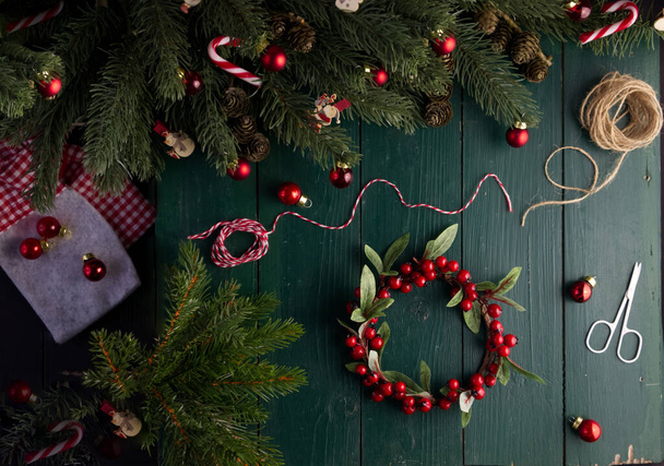 Kadın eli, içinde hediye olan bir keseyi Noel dekorunda yeşil ahşap bir masanın üzerinde hazırlar. - Fotoğraf, Görsel