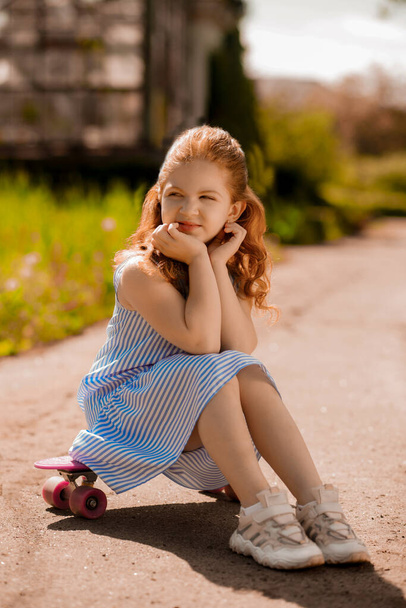 Resting. Pretty little girl sitting on a skateboard - Fotó, kép