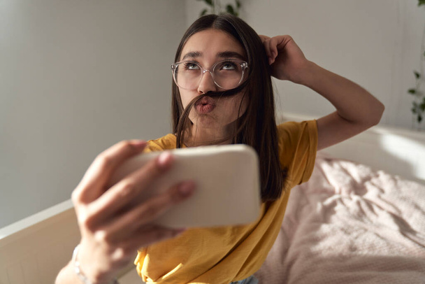 Caucasian teenage girl making funny face while taking selfie - 写真・画像