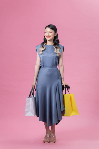 Приваблива усмішка в'єтнамської жінки у високих каблуках і синє плаття, що йде з паперовими сумками. - Фото, зображення
