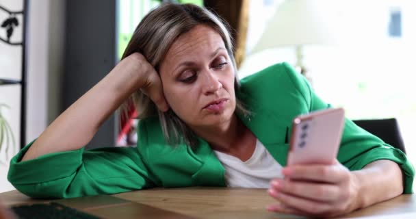 Набридла жінка-фрілансер сидить за столом вдома і використовує смартфон. Менеджер чекає на порядок і нудьгу і лінь
 - Кадри, відео