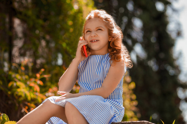 Um telefonema. Menina bonito em um vestido azul falando no telefone - Foto, Imagem