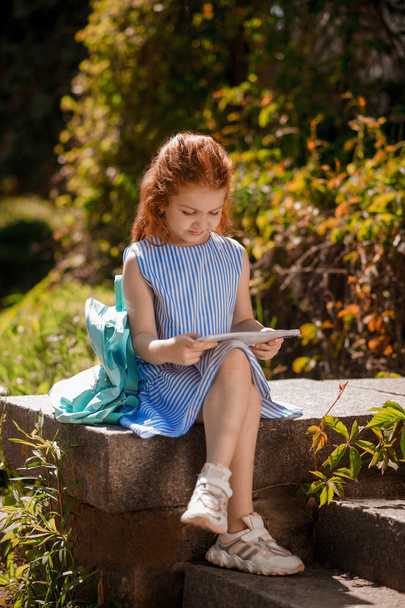 Reading. A girl in a blue dress sitting and holding a book - Photo, Image