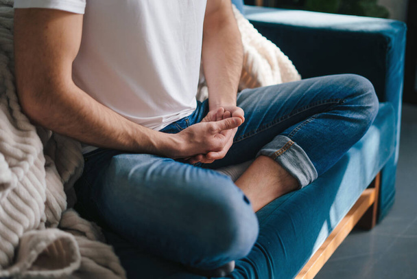 Close-up view of mans legs crossed on sofa and hands crossed in meditation position. Health care. Body care. - Foto, afbeelding