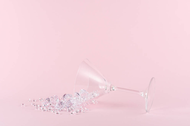 Spilled martini glass full of diamonds on a pink background. Creative minimal party concept. - Photo, image