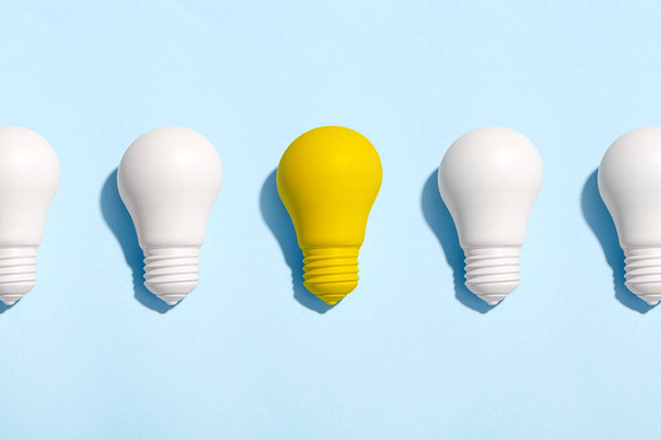 Light bulb success business ideas creativity and inspiration concepts on blue background. Goal achievements flat lay minimalist composition - Foto, afbeelding