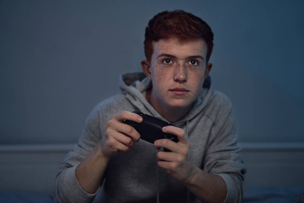 Focus caucasien adolescent garçon jouer sur le contrôleur de jeu la nuit - Photo, image