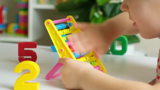 Un niño preescolar juega con ábaco, aprende a contar, hace girar las ruedas de las facturas hacia arriba y hacia abajo. Desarrollo de habilidades motoras finas y matemáticas - Imágenes, Vídeo