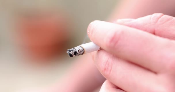 A fiatalember keze égő cigarettát tart. A dohányzás és az onkológia ártalma - Felvétel, videó