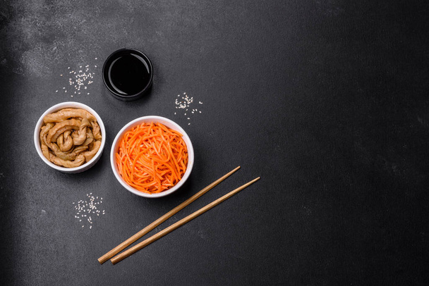 Smaczne pikantne koreańskie marchewki z przyprawami i ziołami na ciemnym betonowym tle. Żywność azjatycka - Zdjęcie, obraz