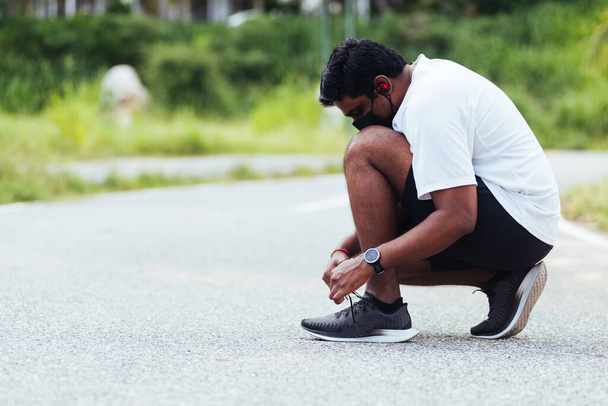 Close up Asian sport runner black man wear watch sitting he trying shoelace running shoes getting ready for jogging and run at the outdoor street health park, healthy exercise workout concept - Valokuva, kuva