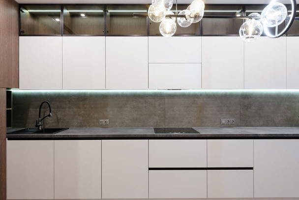 new stylish kitchen with white and dark facades and lighting - Foto, afbeelding