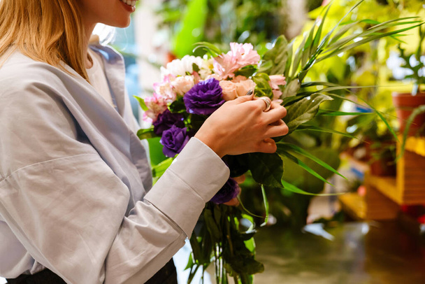 White young woman making bouquet with fresh flowers while working in florist shop - Fotografie, Obrázek