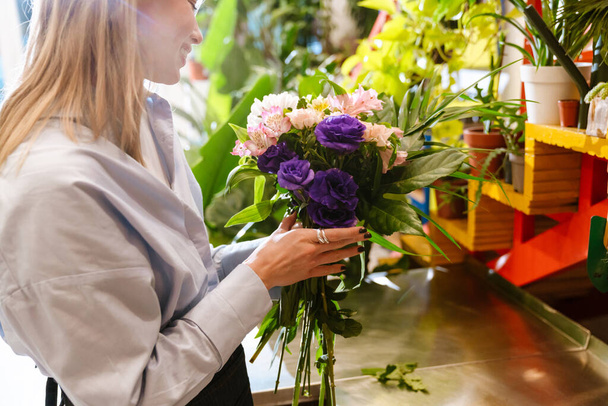 wit mooi jong bloemist meisje maken boeket met verse bloemen in winkel - Foto, afbeelding