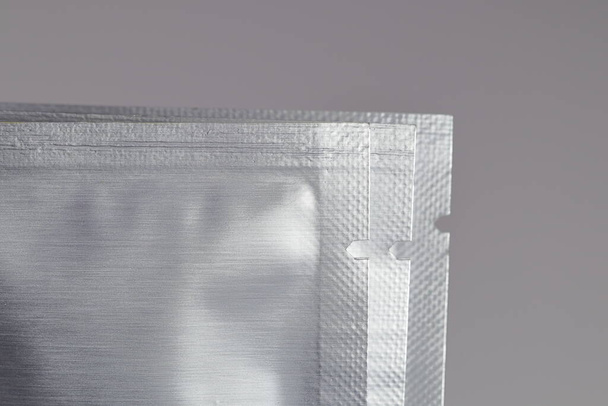 Close up of tear point on sheet foil package. silver plastic sachet mockup sample. Siver pouch, skin mask packaging design. Food zipper bag template, aluminum paper wrapper. - Photo, Image