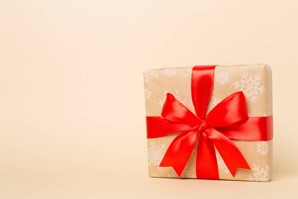 Gift box with red ribbon bow on color background. - Photo, Image