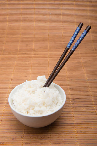 rice bowl with chopsticks on bamboo tablecloth - Foto, afbeelding