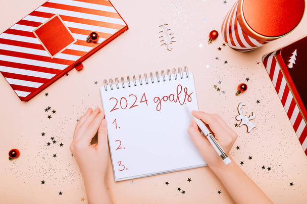 2024 goals writtings in empty notebook. Reusable Red and white boxes for presents in different shapes, gift wrapping and preparation for the festive Christmas holidays season - 写真・画像