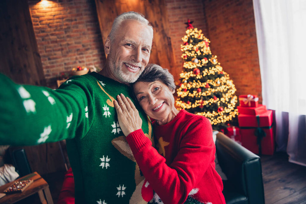 Photo of two positive idyllic partners hug embrace take selfie newyear magic illumination decor indoors. - Photo, Image