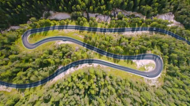 Widok z powietrza krętej drogi z samochodami w słoneczny dzień w lecie w Dolomitach, Włochy. Widok z góry z drona ruchu na górskich drogach, zielone drzewa i łąki alpejskie w Europie. Widok z góry na autostradę - Materiał filmowy, wideo