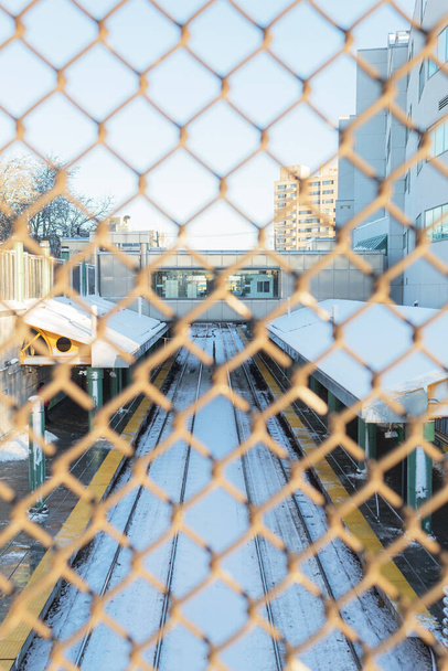 Порожня залізнична станція взимку покрита снігом, який видно ззовні через паркан безпеки. Revere, Massachusetts. - Фото, зображення