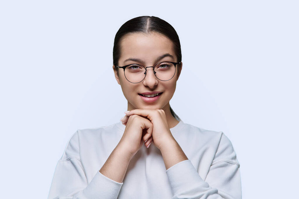Teenage girl in glasses looking at camera on white studio background. Portrait of smart student teenager 14, 15 years old. Adolescence, high school, lifestyle emotions education concept - Photo, image