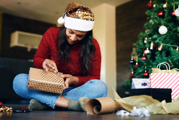 Mujer, Navidad y envoltura de regalo junto al árbol para la temporada festiva, festiva o sorpresa especial en casa. Feliz mujer emocionada ocupada con envoltura de regalo, caja o regalo para la celebración de diciembre en el interior. - Foto, Imagen