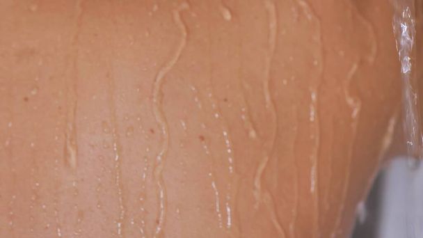 Vue arrière rapprochée de la femme sous la douche avec des gouttes d'eau coulant sur sa peau humide - Photo, image
