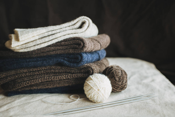 Chaussettes tricotées à la main avec des boules de fil sur un fond sombre. Concept pour la vie lente à la main et hygge. - Photo, image