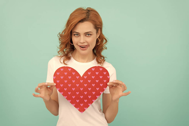smiling redhead lady hold red heart on blue background. - Foto, Imagem