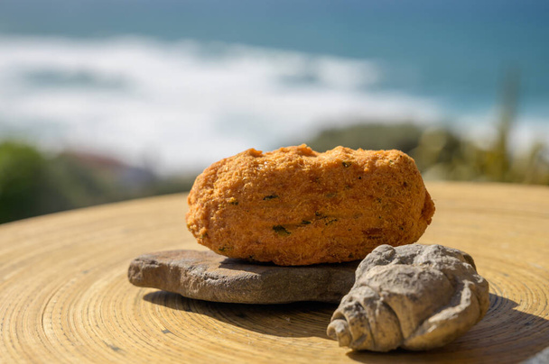 Croquette codfish pastais de bacalhau, tradycyjne portugalskie przekąski serwowane na świeżym powietrzu z widokiem na niebieski ocean Atlantycki w pobliżu Sintra w Lizbonie, Portugalia, zbliżenie - Zdjęcie, obraz